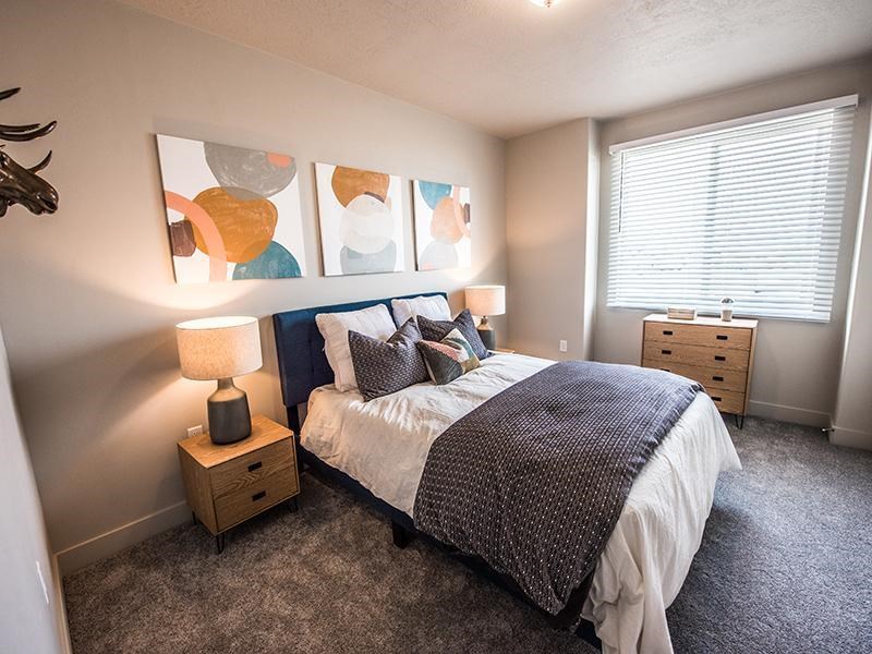 A bedroom with a bed, nightstand, and a deer head on the wall.