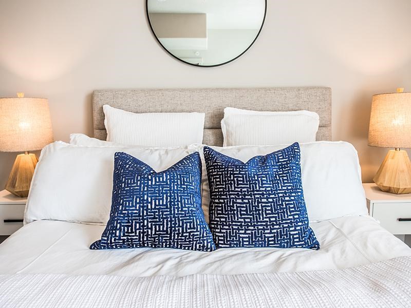 A bed with white sheets and two blue patterned pillows.