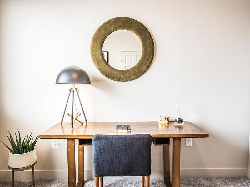 A table with a chair and a mirror on the wall.