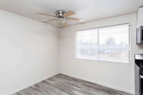 A room with a ceiling fan and a window with blinds.