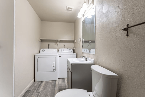 A small bathroom with a toilet, sink, and a washer and dryer.