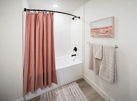 A bathroom with a pink shower curtain and a white bathtub.