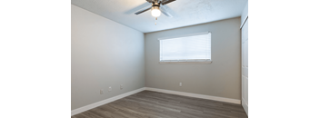 A room with a ceiling fan and a window with blinds.