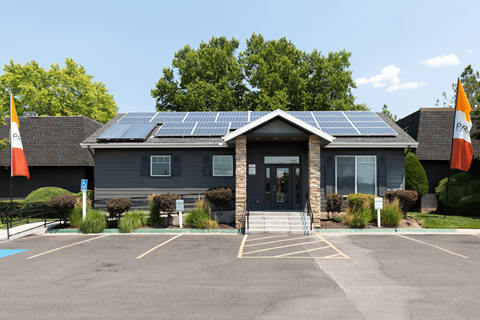 A building with solar panels on the roof and flags on the front.