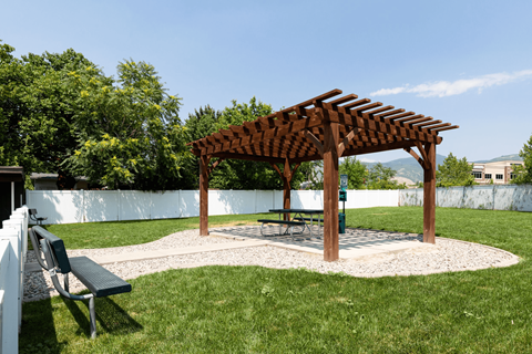 A wooden pergola is situated in a grassy area.