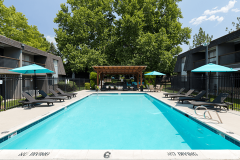 A large swimming pool surrounded by lounge chairs and umbrellas.