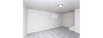 A room with a grey carpet and a window with blinds.