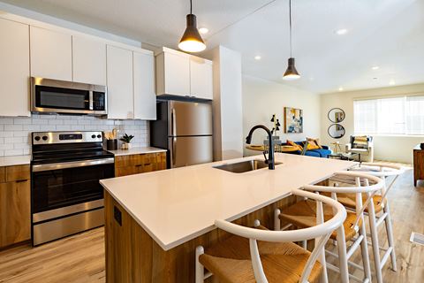 a kitchen with white cabinets and a large white island with a sink and chairs