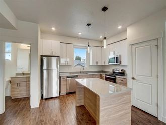 an open kitchen with an island and a stainless steel refrigerator