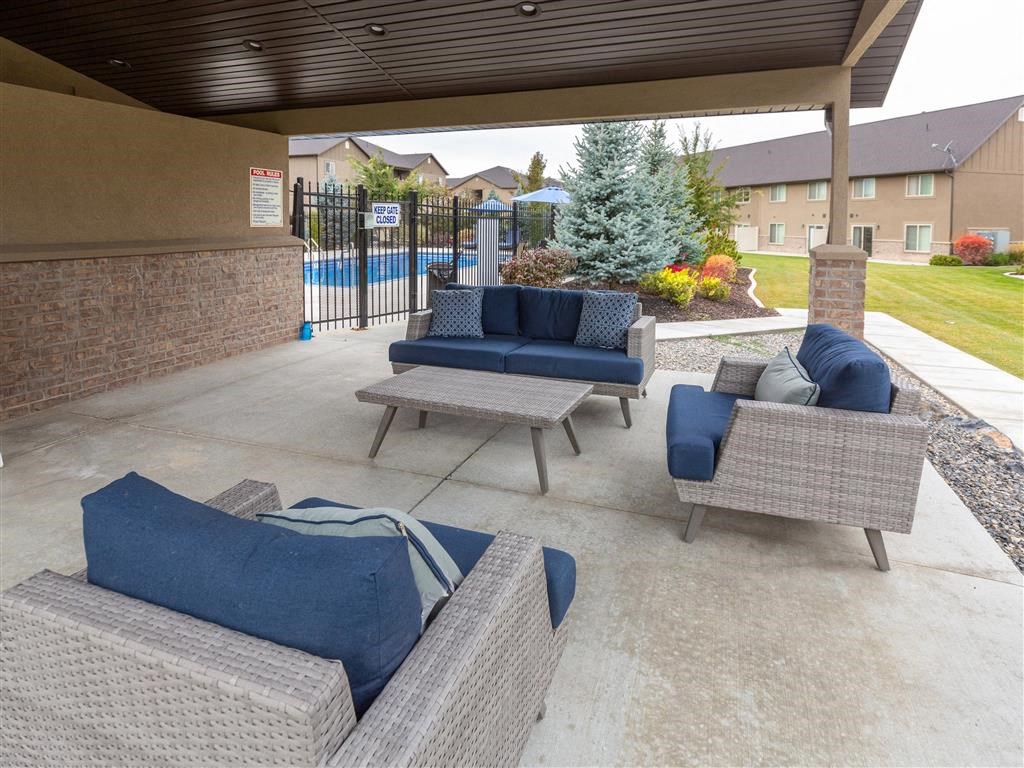 a covered patio with couches and chairs and a pool