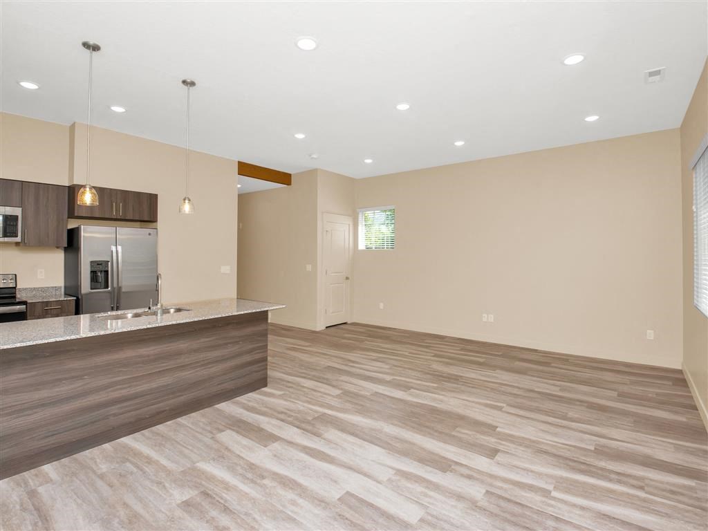 the kitchen and living room of an empty house with a refrigerator and a sink
