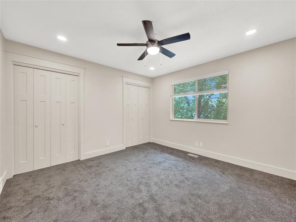 a carpeted room with a ceiling fan and a window
