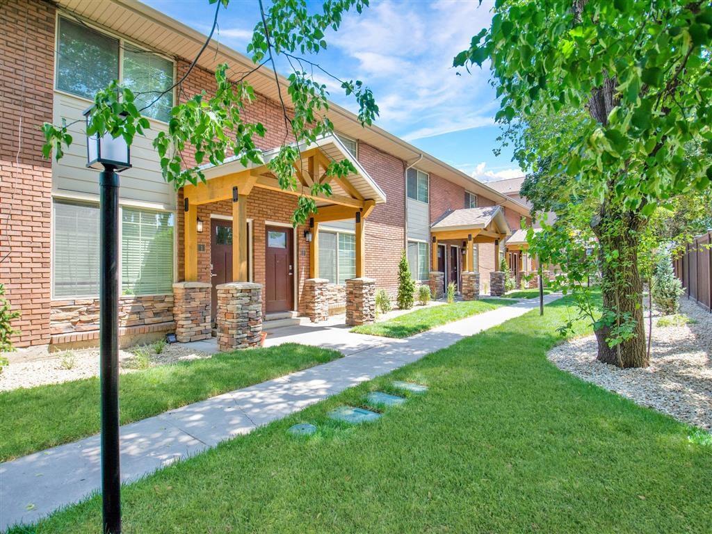a sidewalk in front of a brick building with grass and trees