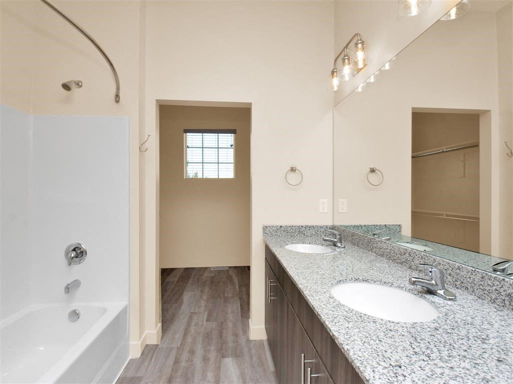 a bathroom with two sinks and a tub and a mirror