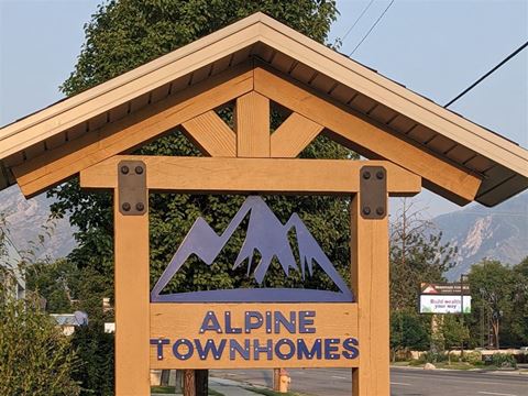 a sign for alpine townhomes on the side of a street