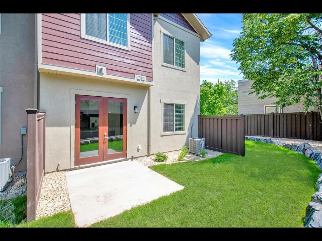 a patio in front of a house with a yard and a fence