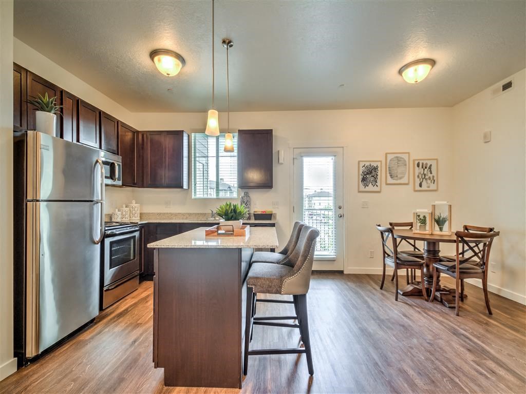 a kitchen with a large island and a stainless steel refrigerator at Aderra apartments for rent in Roy, Utah
