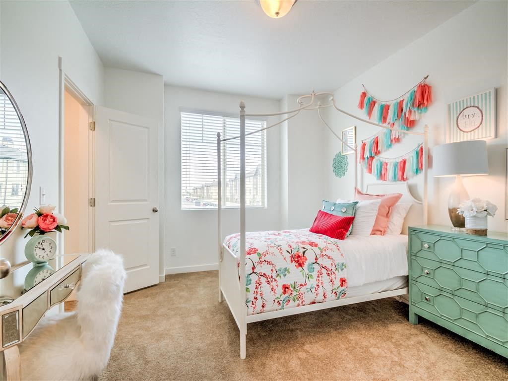 a bedroom with a bed and a dresser and a window at Aderra apartment complex for rent in Roy, Utah