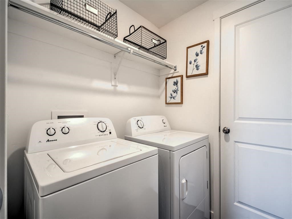 a white laundry room with two washes and a dryer at Aderra apartment complex in Roy, Utah