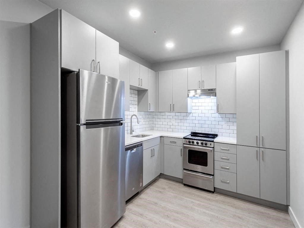 a white kitchen with stainless steel appliances and white cabinets