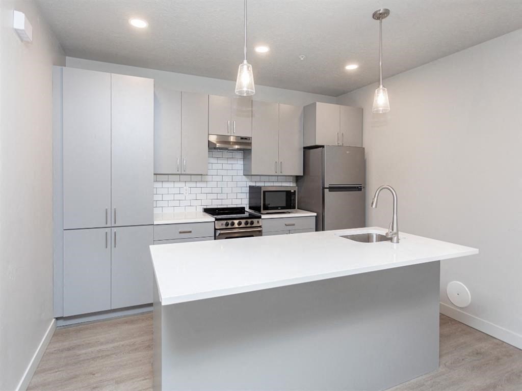a white kitchen with stainless steel appliances and a large island