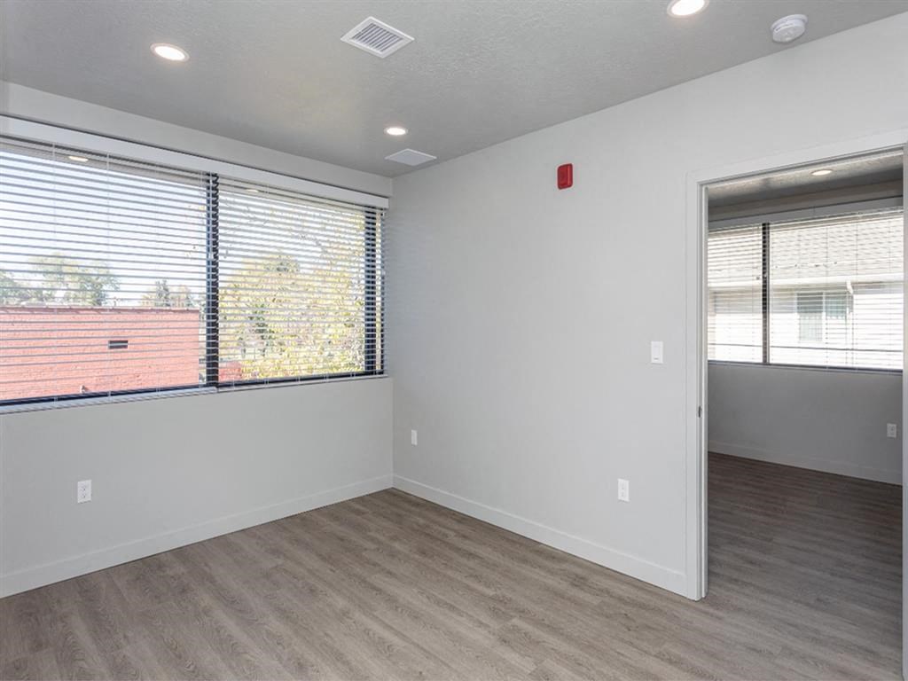 an empty living room with a large window and wood flooring
