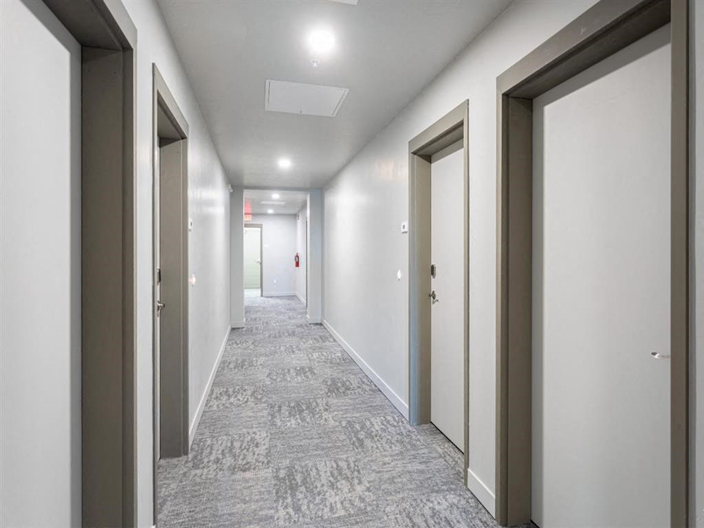 a corridor with doors and white walls and a carpeted floor