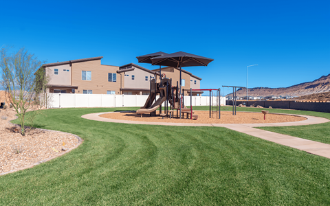 A playground with a slide and a swing set in a grassy area.