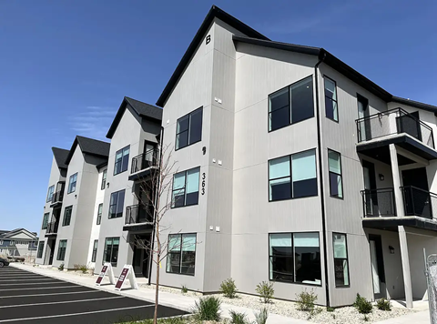 A modern apartment building with a parking lot in front.