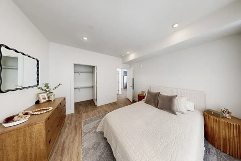 A bedroom with a large bed and a wooden dresser.