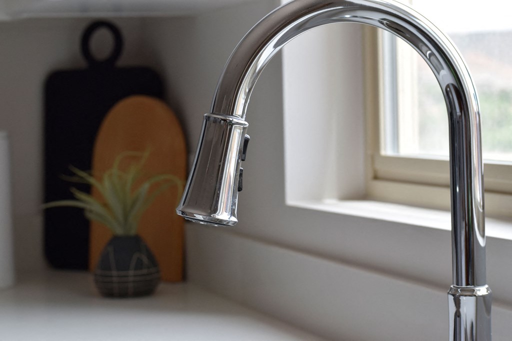 a kitchen sink with a faucet in front of a window