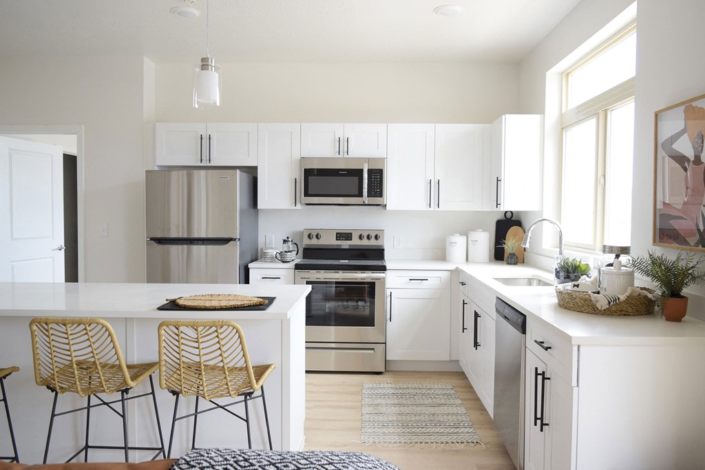 a kitchen with white cabinets and a white island with two stools