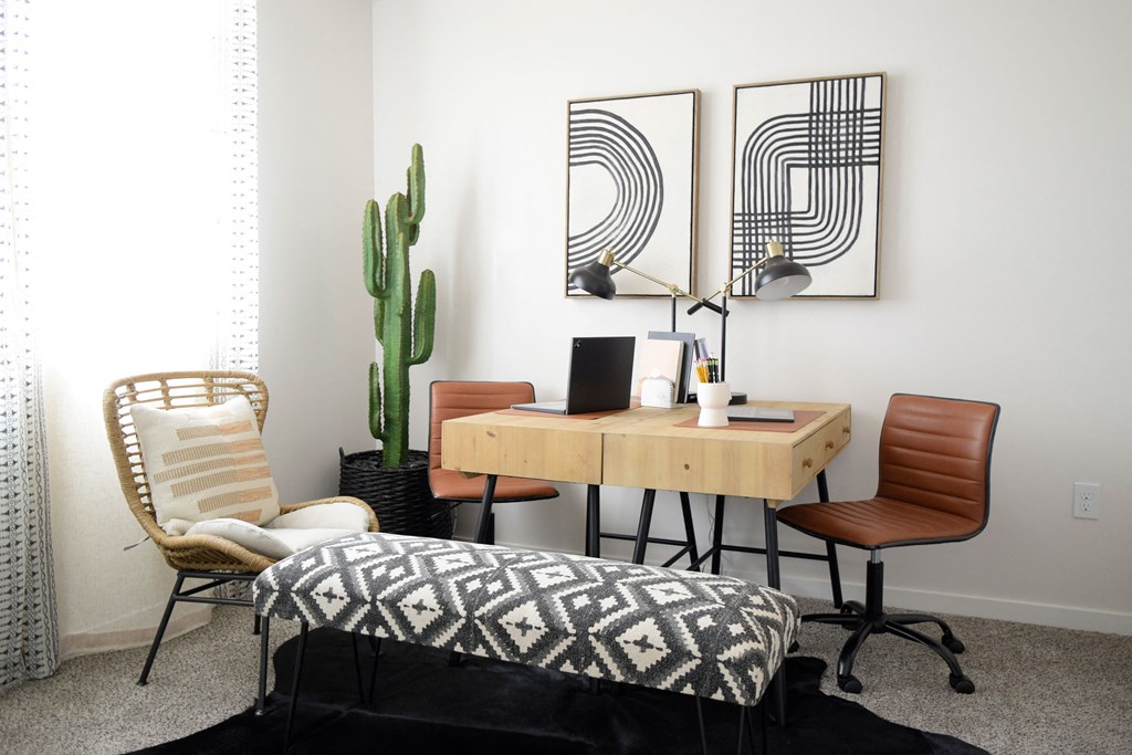 a home office with three chairs and a desk with a computer and a cactus