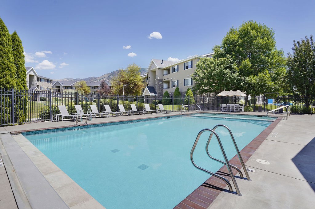 A swimming pool with a diving board in front of a resort.