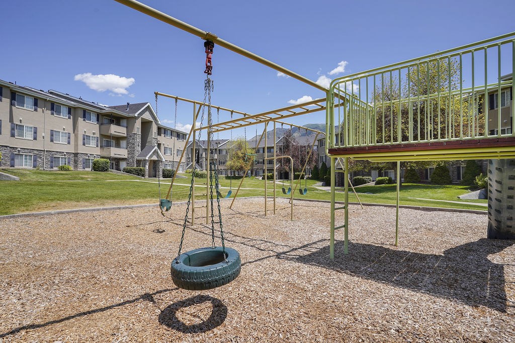 A tire swing hangs from a metal frame in a playground.