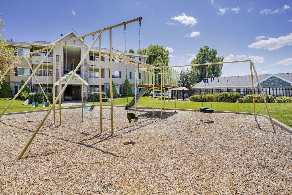 A playground with a swing set and a building in the background.