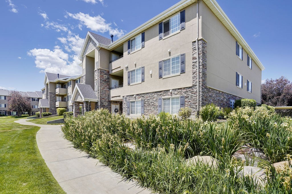 Apartment building with a stone facade and a green lawn in front.