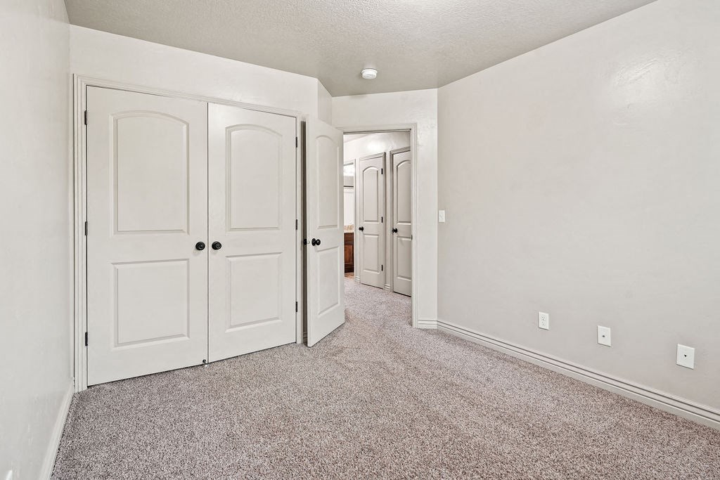 an empty bedroom with white doors and carpeting