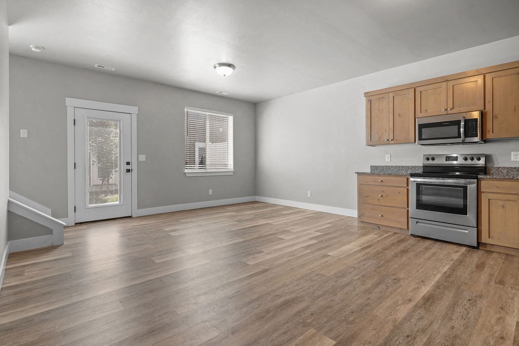 the kitchen and living room of a house with wood floors and stainless steel appliances
