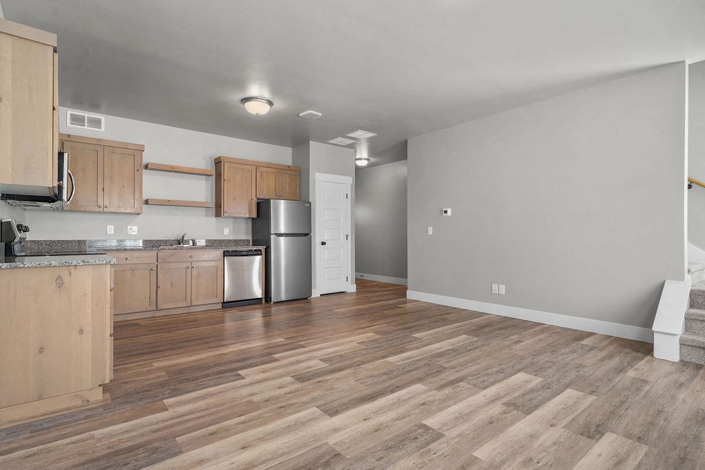 a kitchen with wooden floors and a stainless steel refrigerator