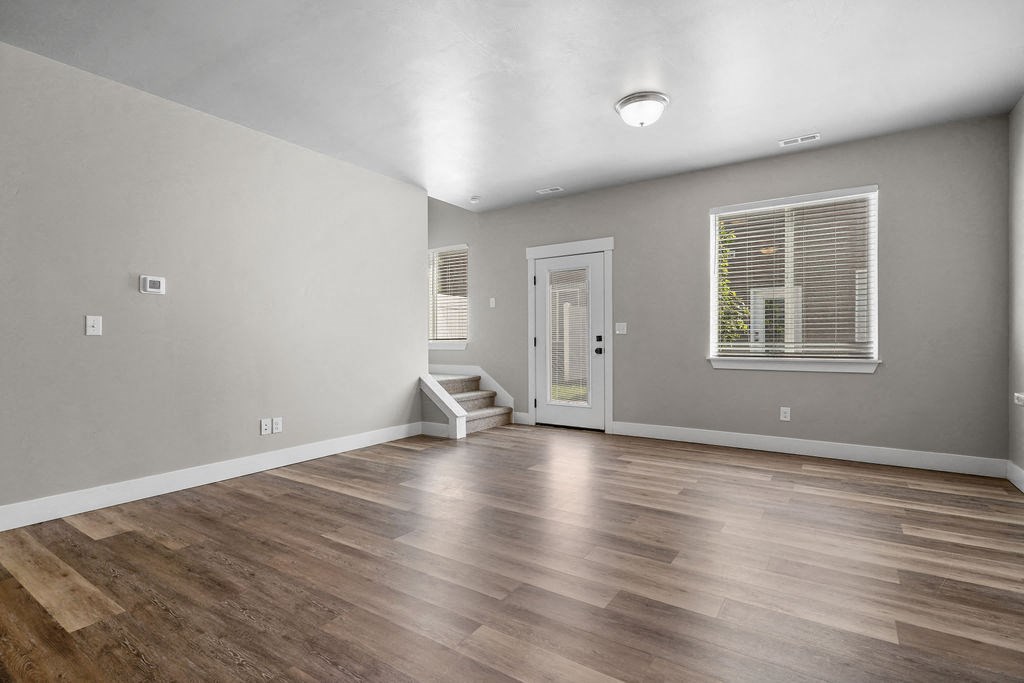 the living room is spacious and has a large window and hardwood floors