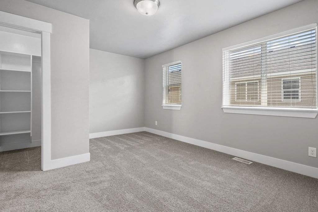 an empty living room with two windows and a door to a closet