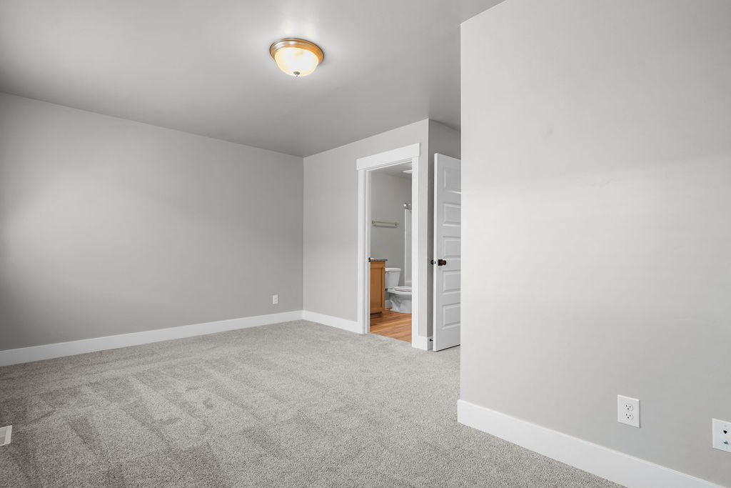 a bedroom with a carpeted floor and a door to a bathroom