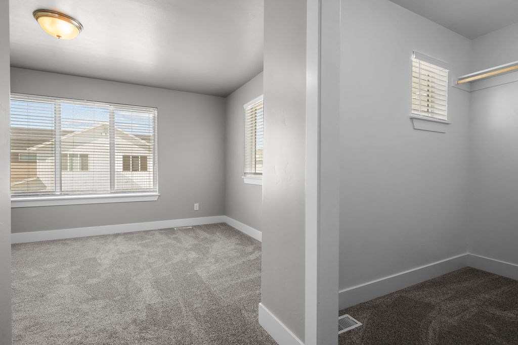 a bedroom with a large window and carpeted flooring