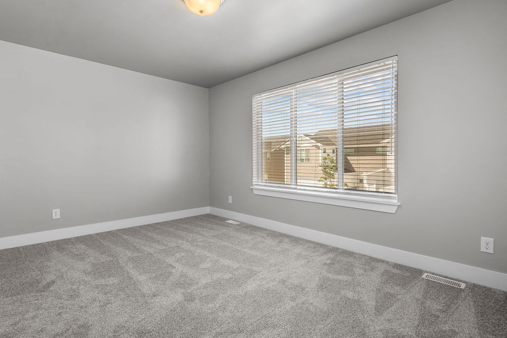 an empty living room with a window and carpet