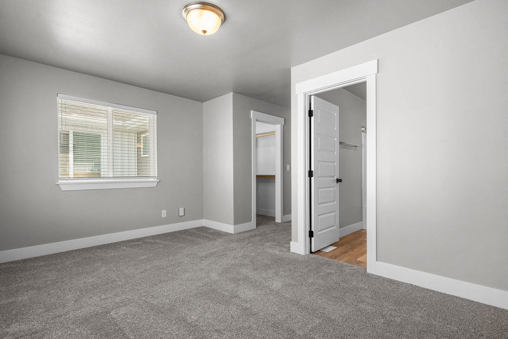 a bedroom with a door to a closet and a window