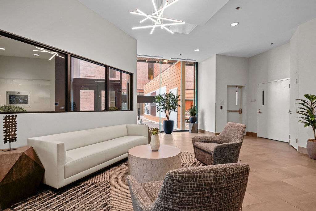 A white couch sits in a room with brown chairs and a table.