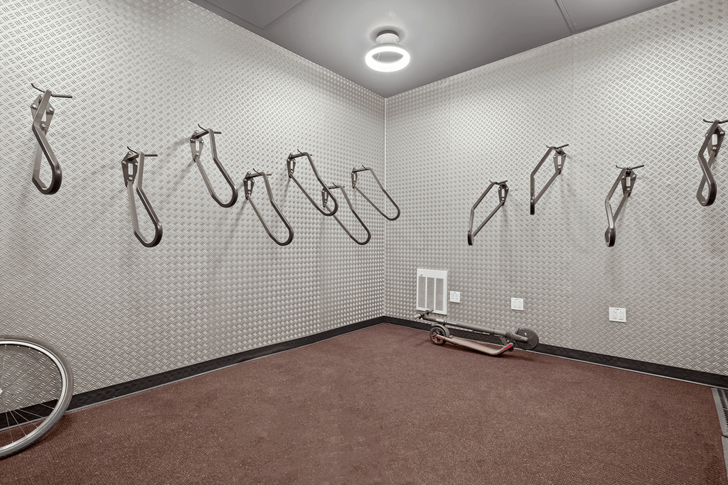 A room with a wall of hooks and a bicycle wheel on the floor.