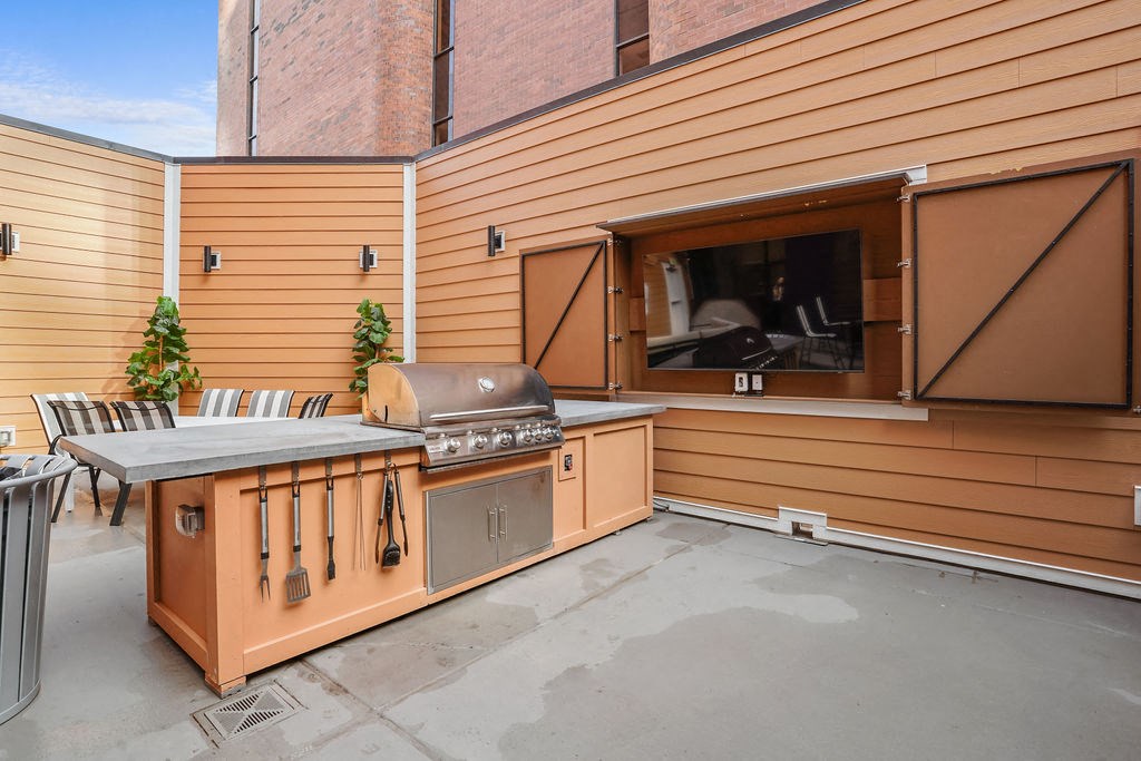 A wooden outdoor kitchen with a grill and sink.