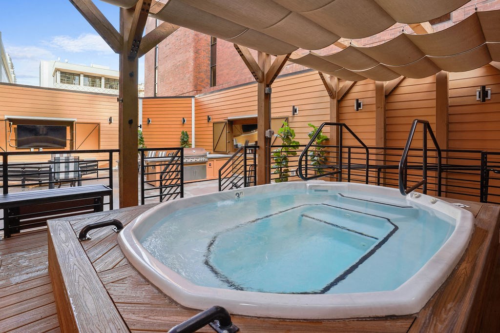 A hot tub on a wooden deck with a canopy over it.